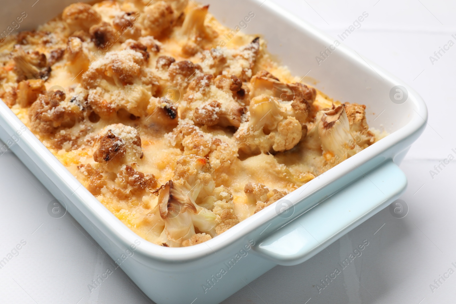 Photo of Tasty baked cauliflower on white tiled table, closeup