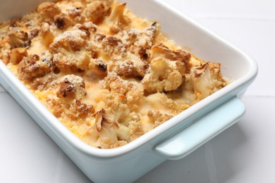 Tasty baked cauliflower on white tiled table, closeup