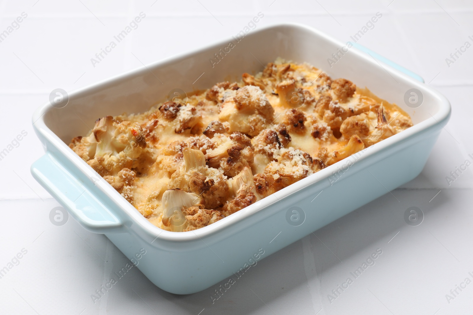 Photo of Tasty baked cauliflower on white tiled table, closeup