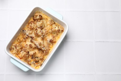 Tasty baked cauliflower on white tiled table, top view. Space for text