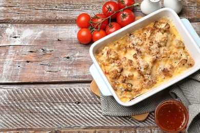 Tasty baked cauliflower, spices and tomato on wooden table, flat lay. Space for text