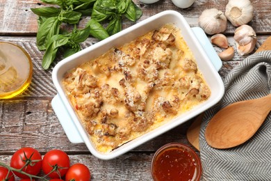 Photo of Tasty baked cauliflower, sauce, oil and products on wooden table, flat lay