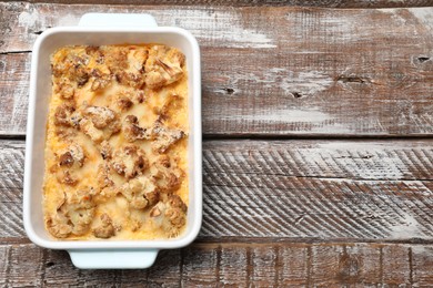 Photo of Tasty baked cauliflower on wooden table, top view. Space for text