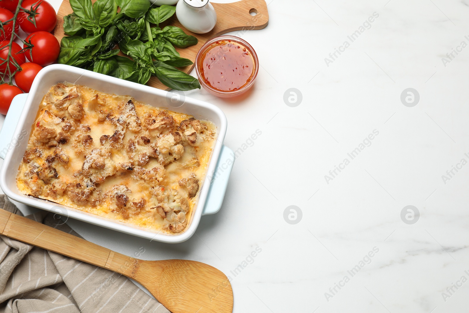 Photo of Tasty baked cauliflower, sauce, basil and tomatoes on white marble table, flat lay. Space for text