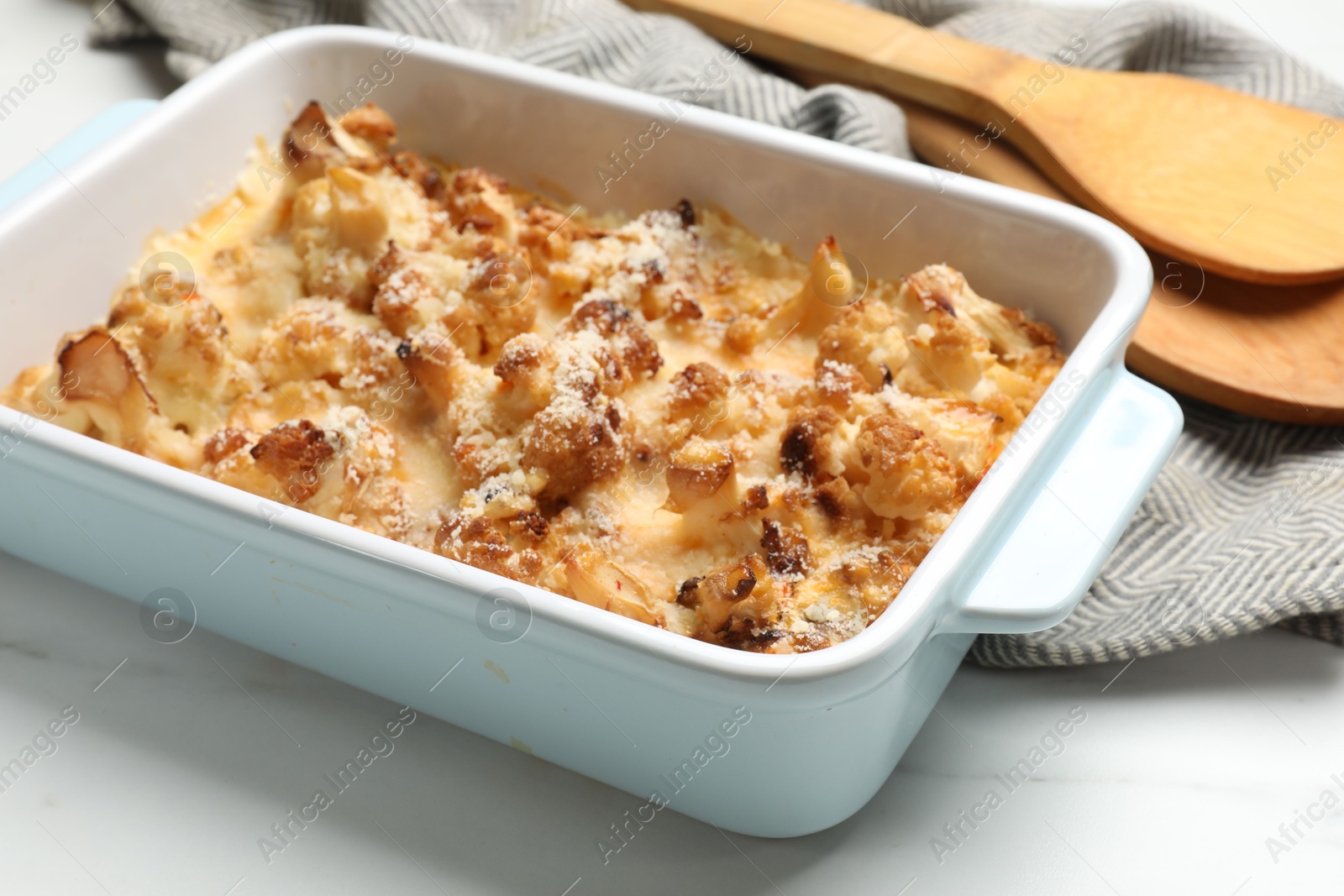 Photo of Tasty baked cauliflower in baking dish on white marble table, closeup