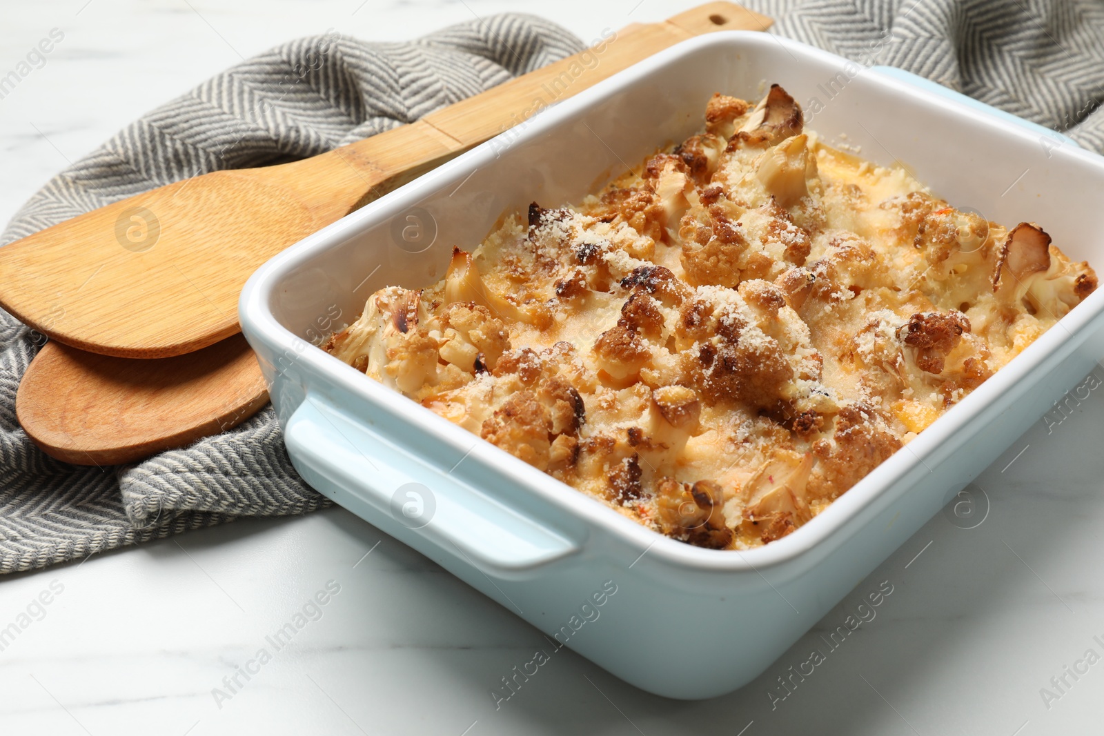 Photo of Tasty baked cauliflower in baking dish on white marble table, closeup