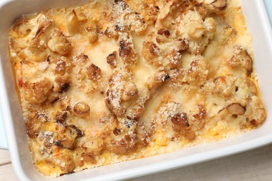 Photo of Tasty baked cauliflower in baking dish on light wooden table, top view