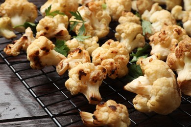 Cooling rack with tasty baked cauliflower and parsley on wooden table, closeup