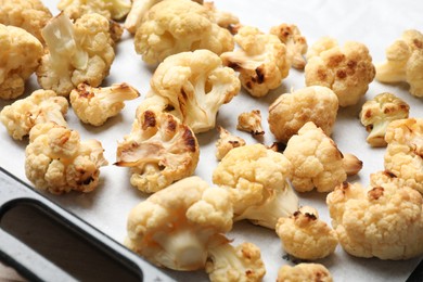 Photo of Tasty baked cauliflower on baking tray, closeup