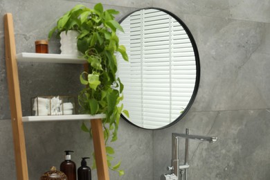 Photo of Round mirror on grey tiled wall in bathroom