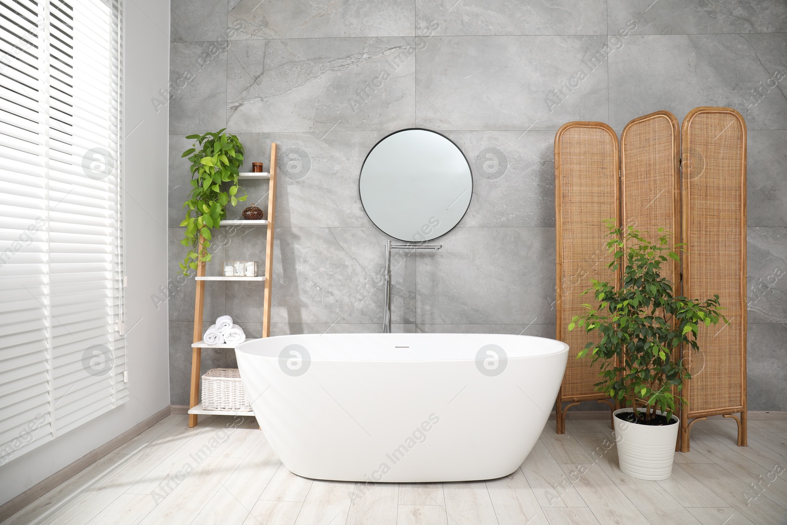 Photo of Wooden folding screen, bathtub, houseplants and mirror in bathroom. Interior design