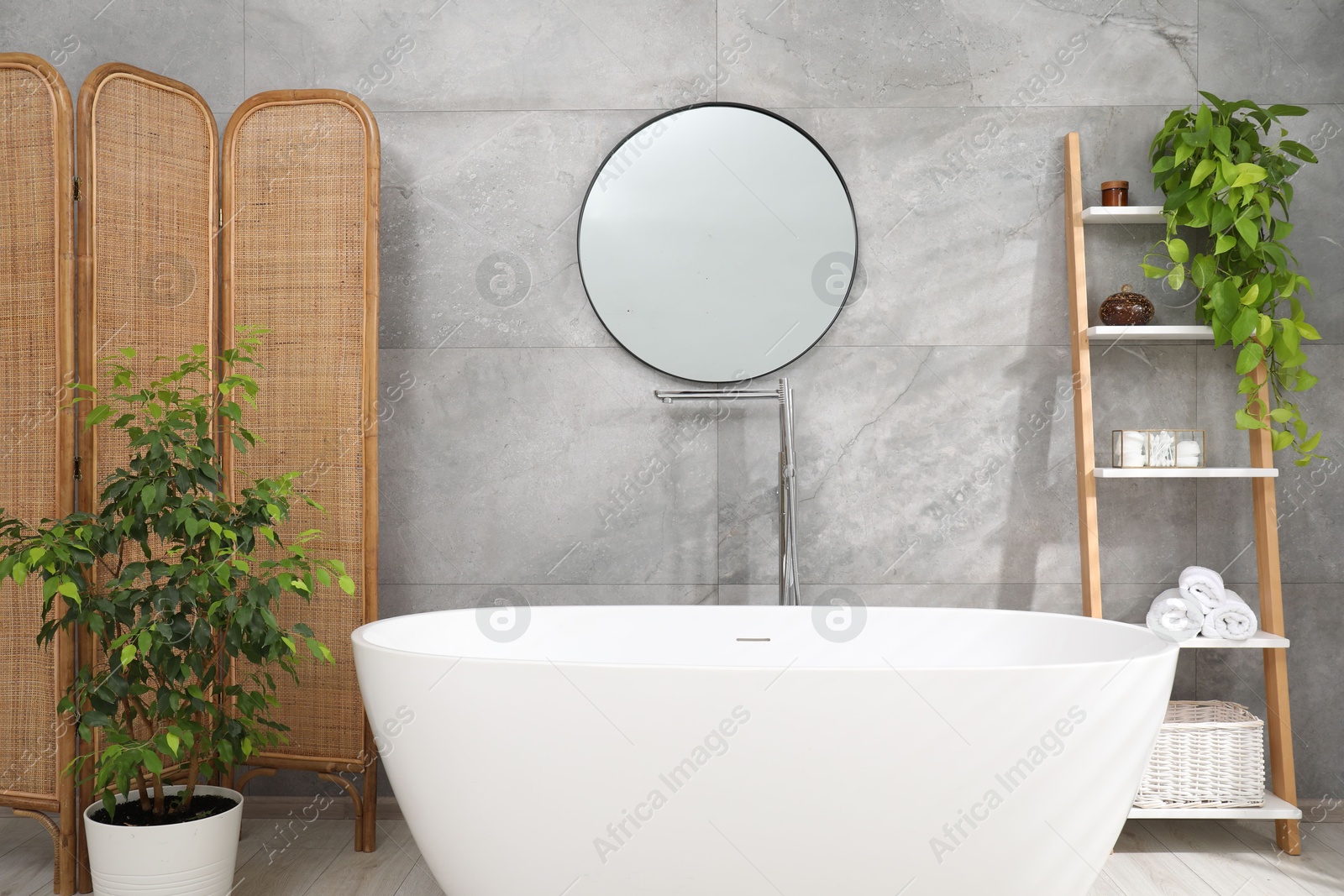 Photo of Wooden folding screen, bathtub, houseplants and mirror in bathroom. Interior design