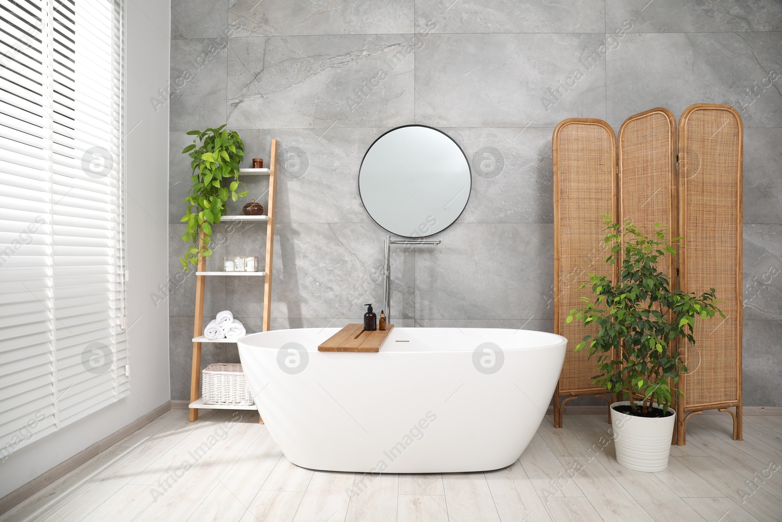 Photo of Wooden folding screen, bathtub, houseplants and mirror in bathroom. Interior design