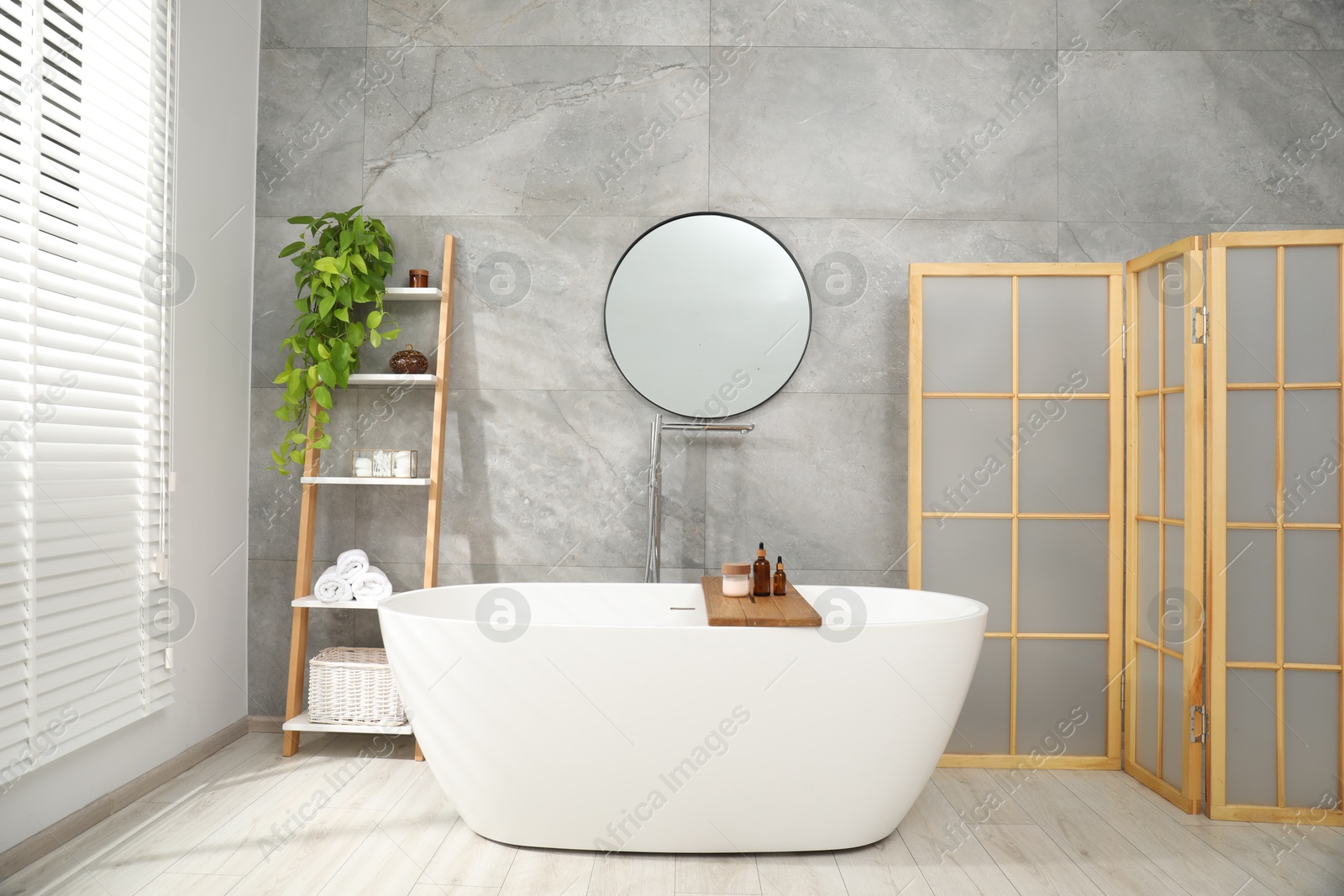 Photo of Folding screen, bathtub, houseplant and mirror in bathroom. Interior design