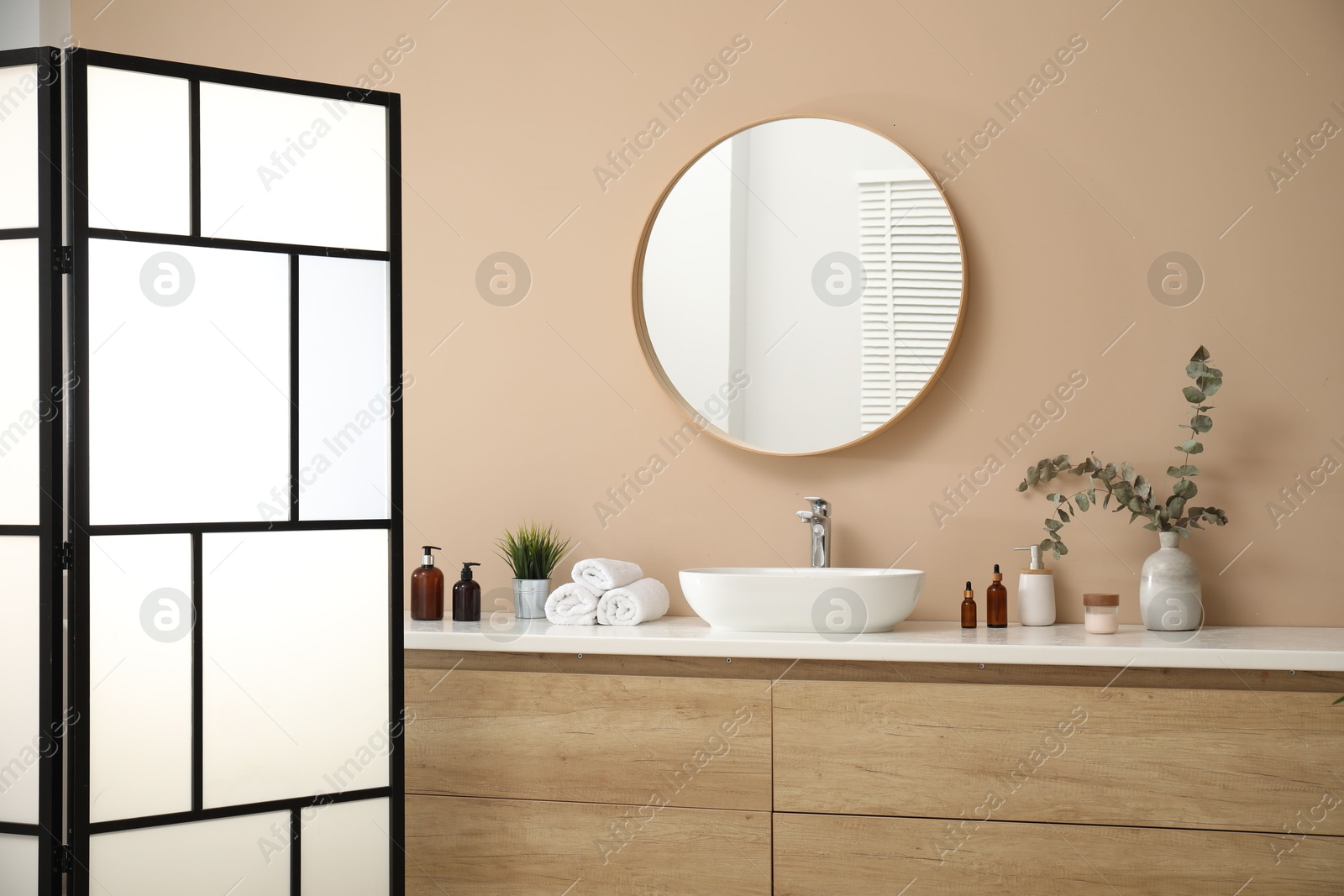 Photo of Folding screen, vanity, sink, mirror and floral decor in bathroom. Interior design