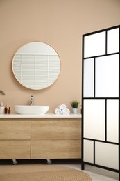 Folding screen, vanity, sink, mirror and floral decor in bathroom. Interior design