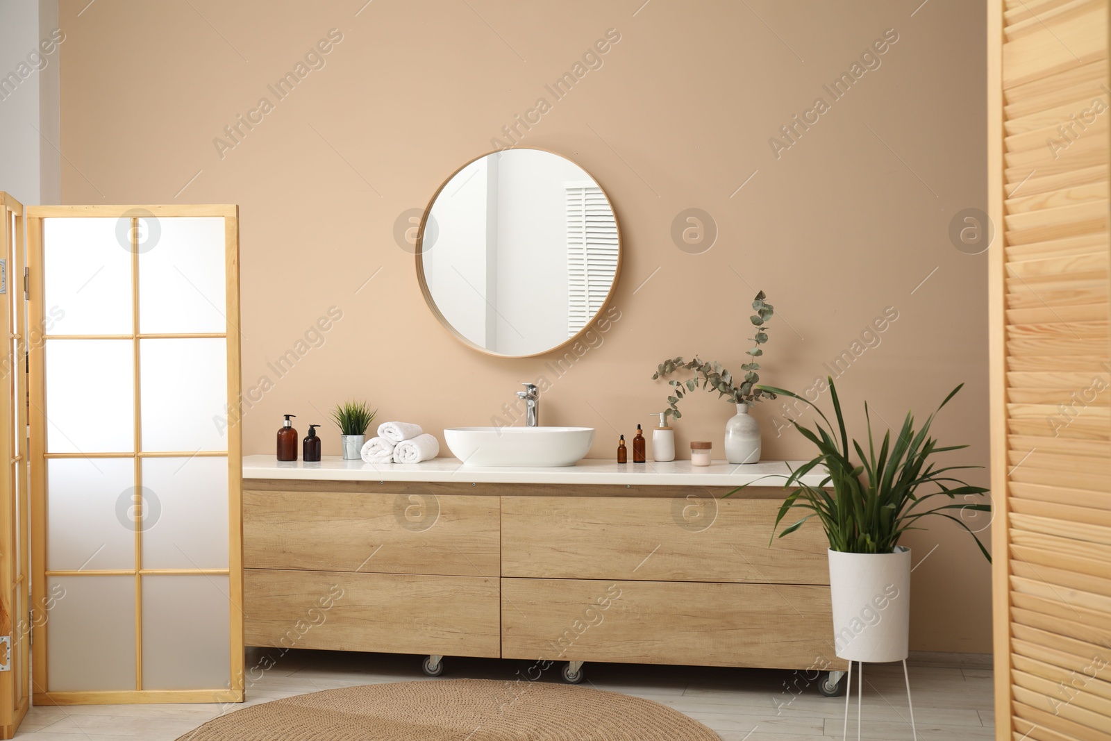 Photo of Folding screen, vanity, sink, mirror and floral decor in bathroom. Interior design