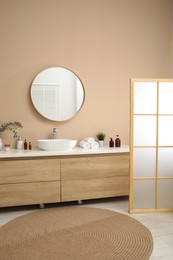 Photo of Folding screen, vanity, sink, mirror and floral decor in bathroom. Interior design