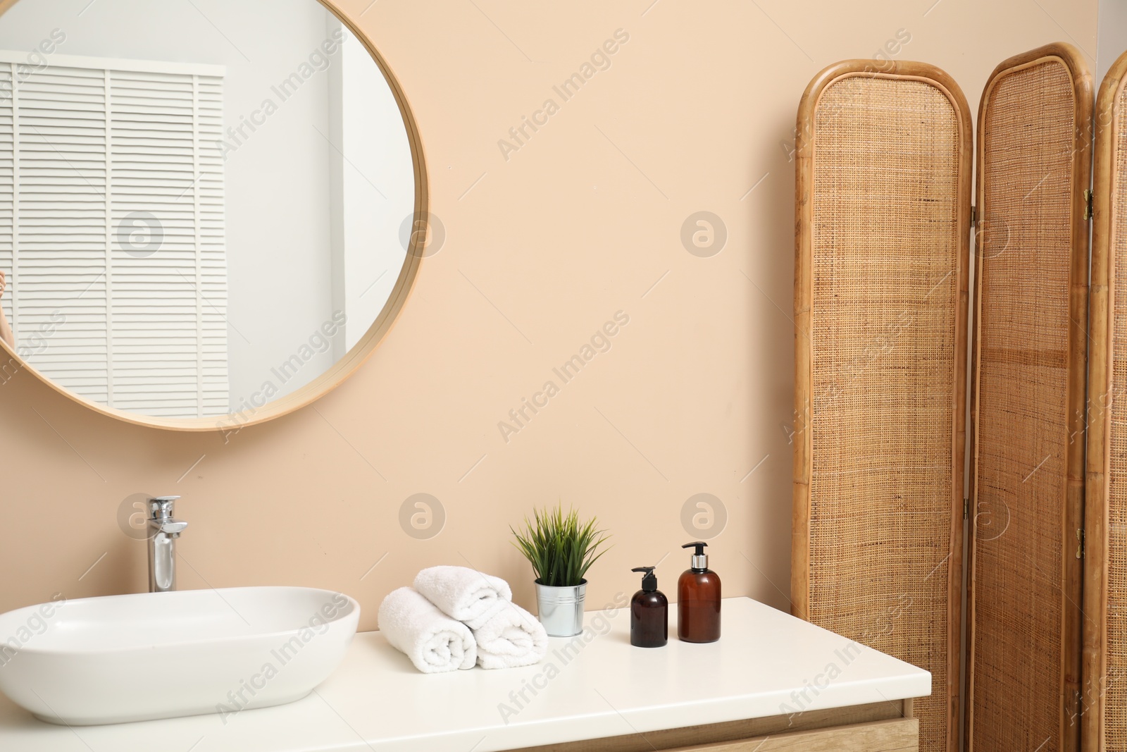 Photo of Folding screen, vanity, sink, mirror and floral decor in bathroom. Interior design