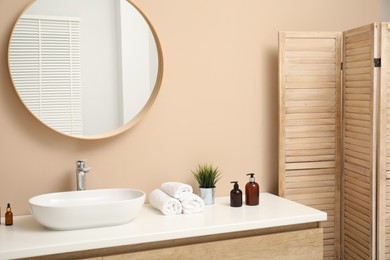 Folding screen, vanity, sink, mirror and floral decor in bathroom. Interior design