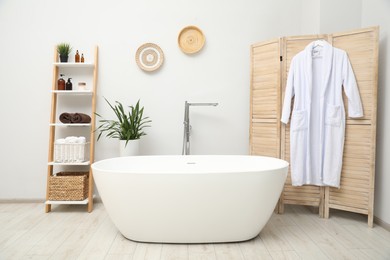 Photo of Stylish bathroom interior with folding screen and tub