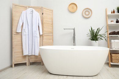 Photo of Stylish bathroom interior with folding screen and tub