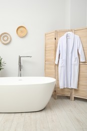 Photo of Stylish bathroom interior with folding screen and tub