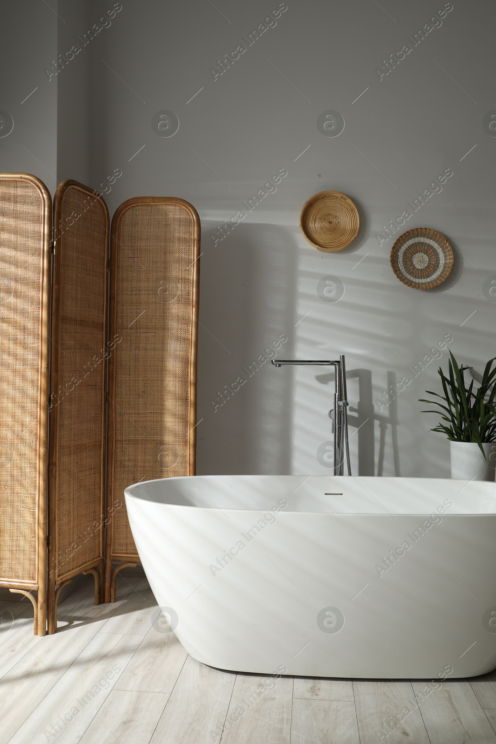 Photo of Stylish bathroom interior with folding screen and tub