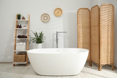 Photo of Stylish bathroom interior with folding screen and tub