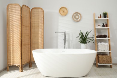 Photo of Stylish bathroom interior with folding screen and tub