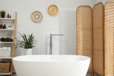 Photo of Stylish bathroom interior with folding screen and tub