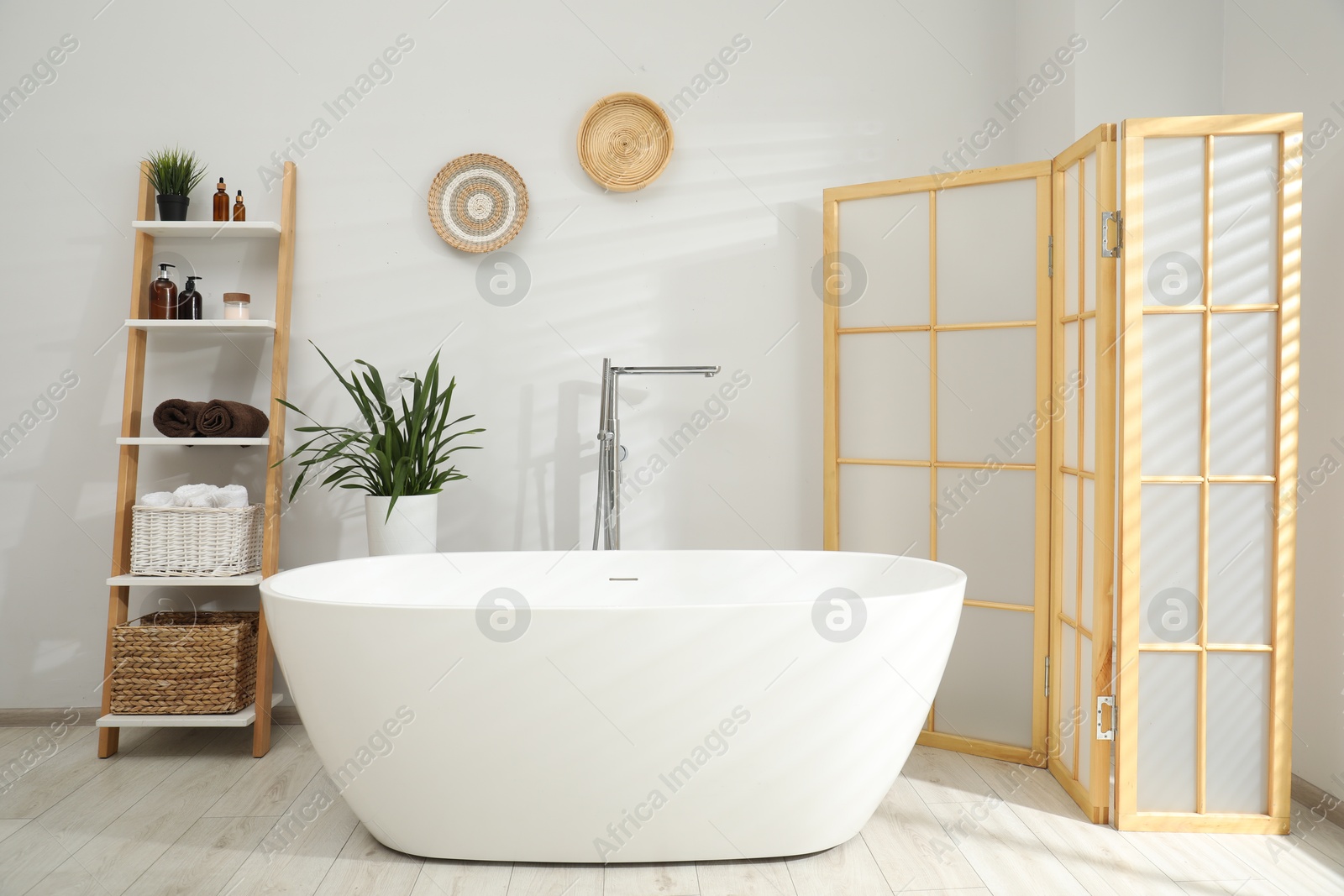 Photo of Stylish bathroom interior with folding screen and tub