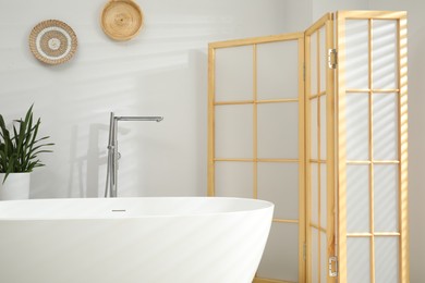 Photo of Stylish bathroom interior with folding screen and tub