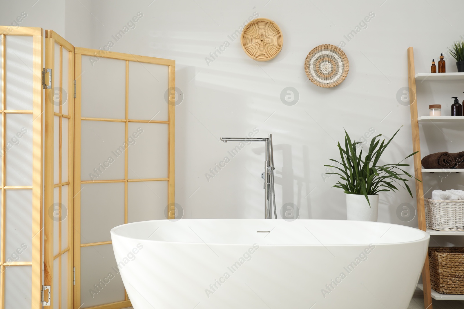 Photo of Stylish bathroom interior with folding screen and tub