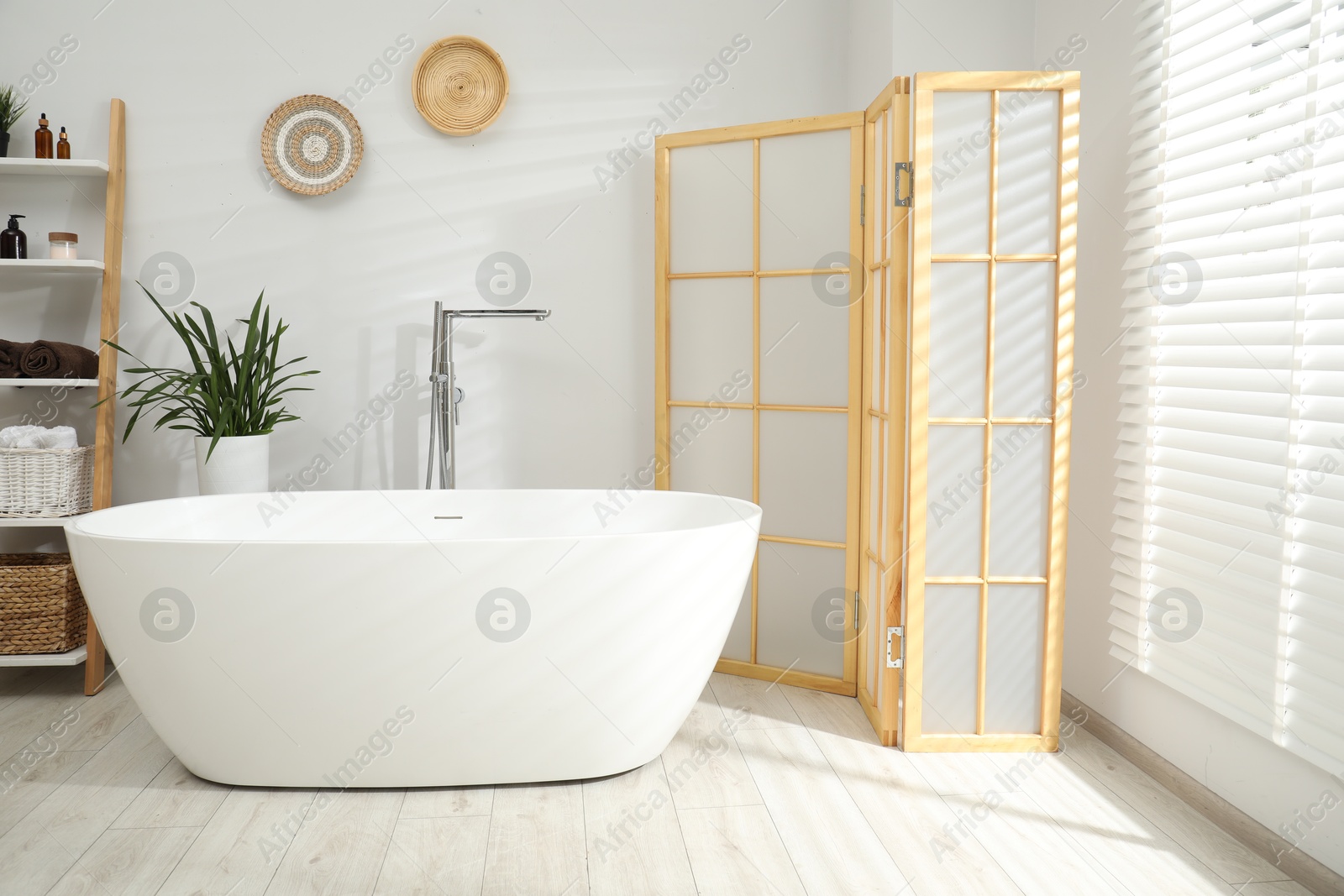 Photo of Stylish bathroom interior with folding screen and tub