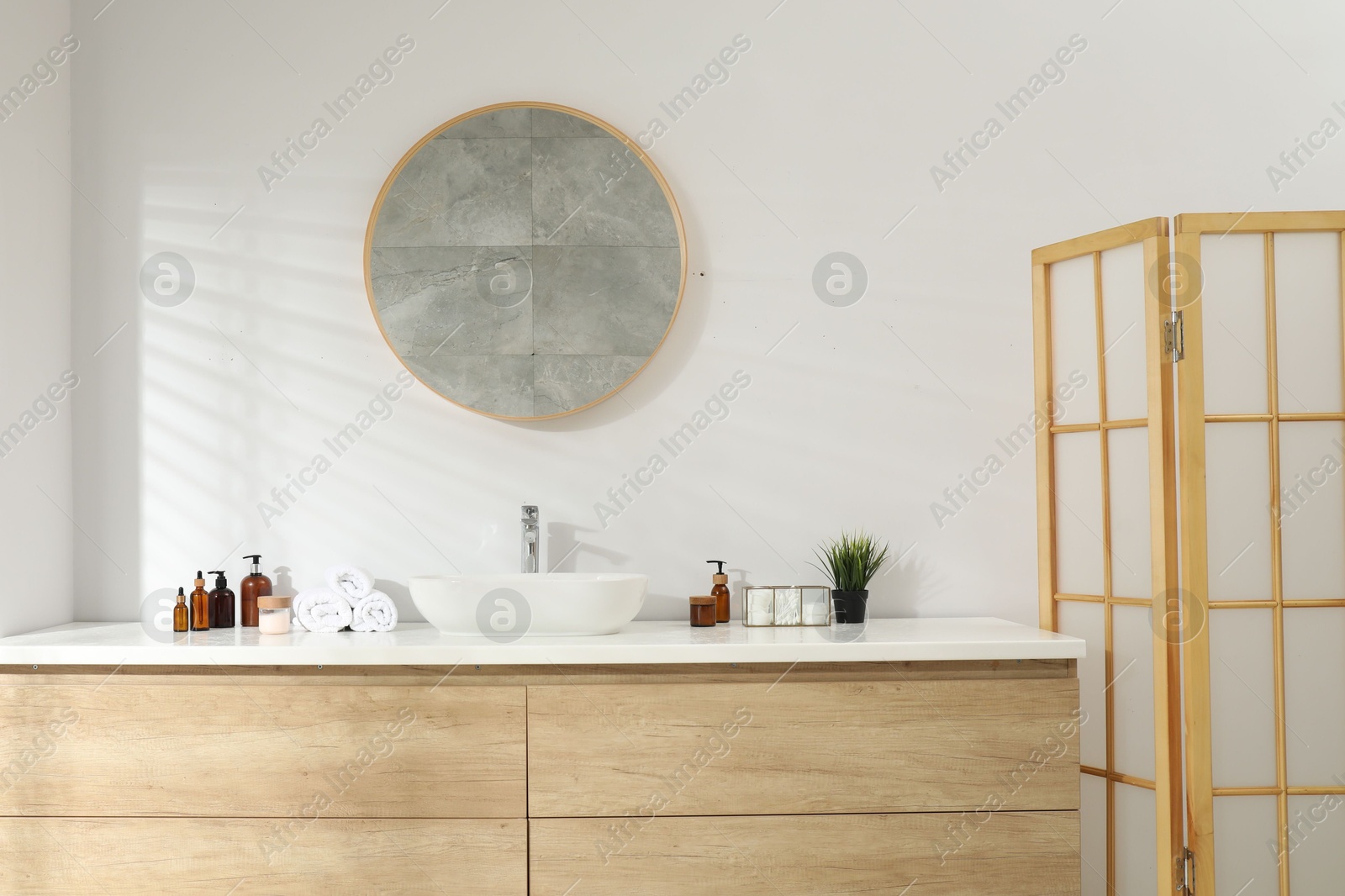 Photo of Folding screen and round mirror over sink in bathroom. Interior design