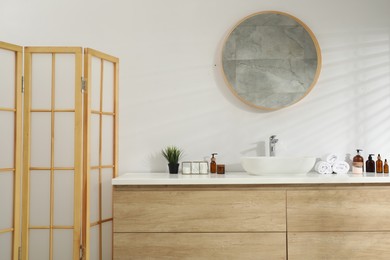 Photo of Folding screen and round mirror over sink in bathroom. Interior design