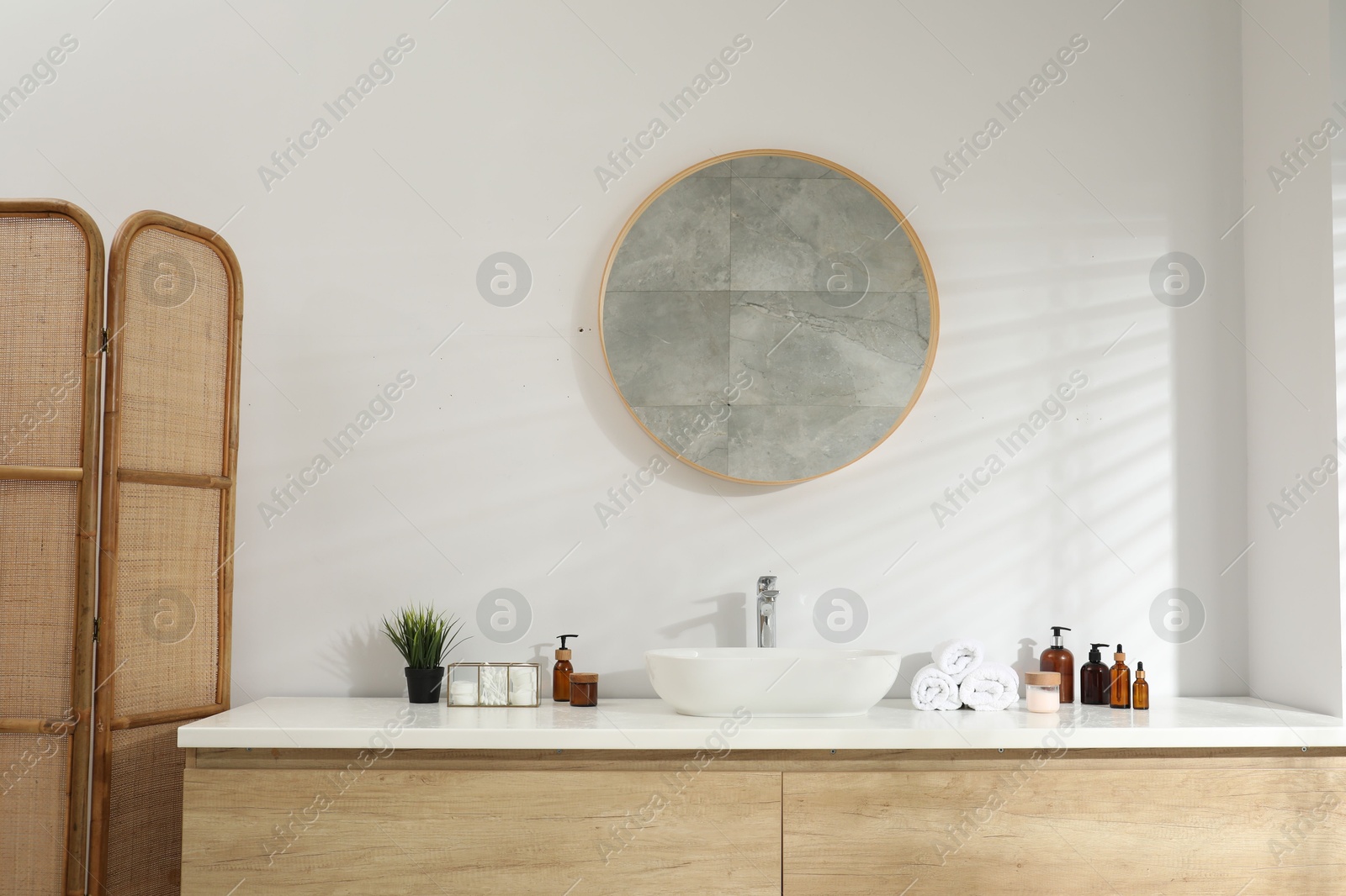 Photo of Folding screen and round mirror over sink in bathroom. Interior design