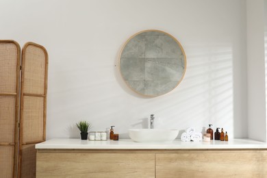 Photo of Folding screen and round mirror over sink in bathroom. Interior design