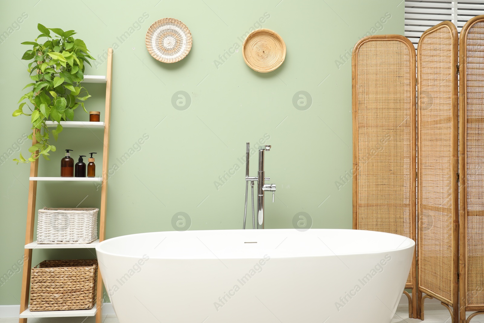 Photo of Stylish bathroom interior with folding screen and tub