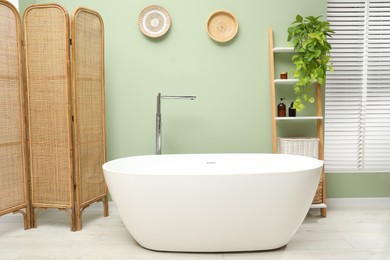 Photo of Stylish bathroom interior with folding screen and tub