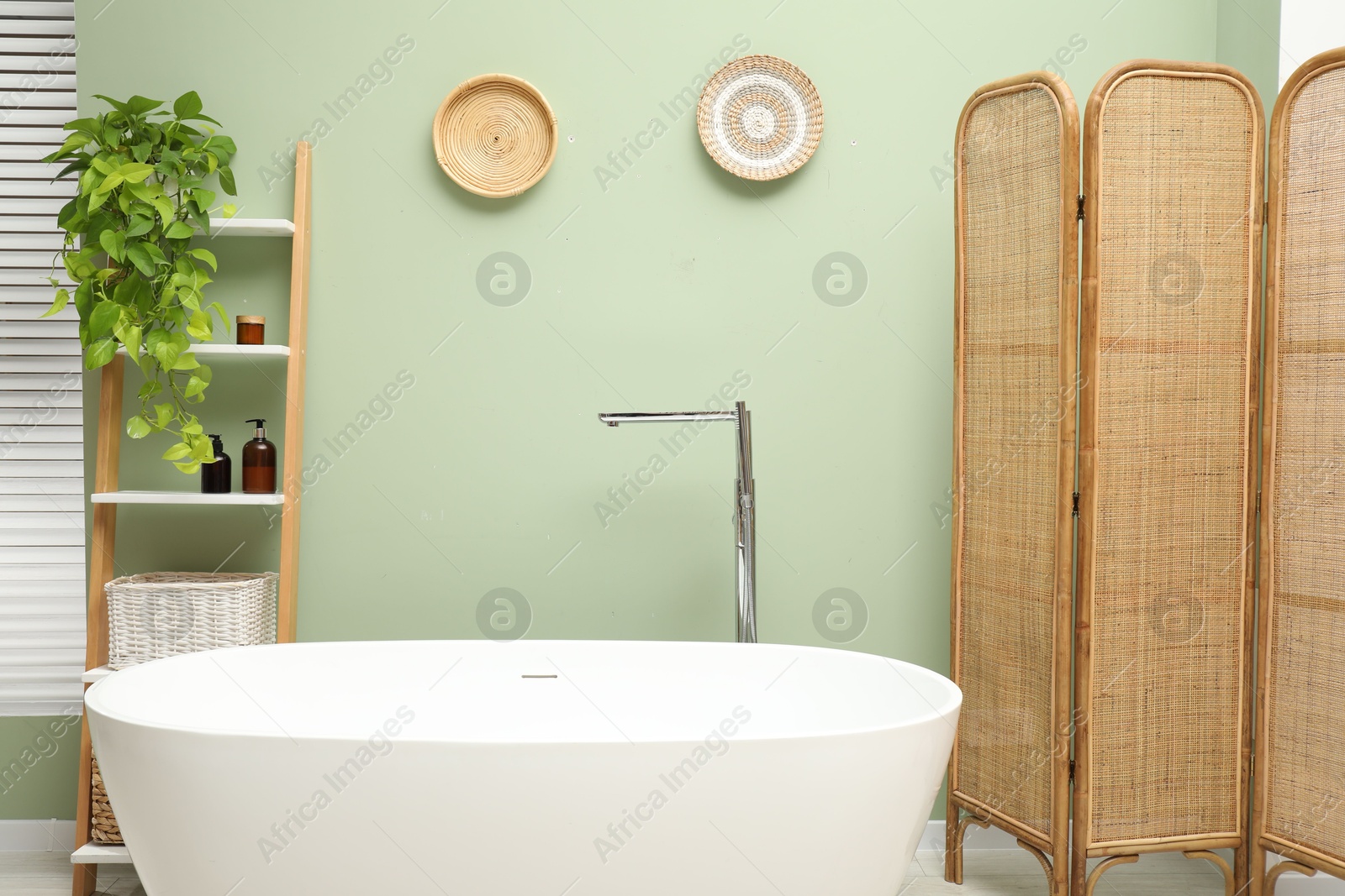 Photo of Stylish bathroom interior with folding screen and tub