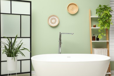 Photo of Stylish bathroom interior with folding screen and tub