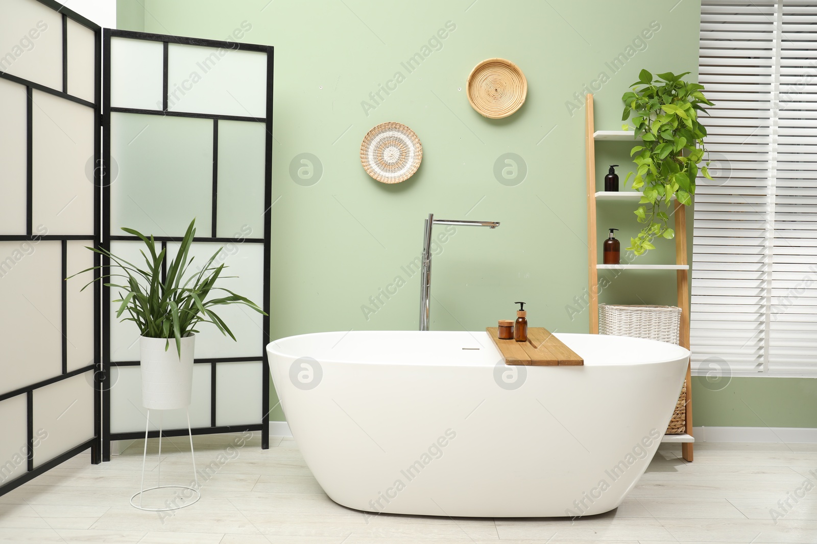 Photo of Stylish bathroom interior with folding screen and tub