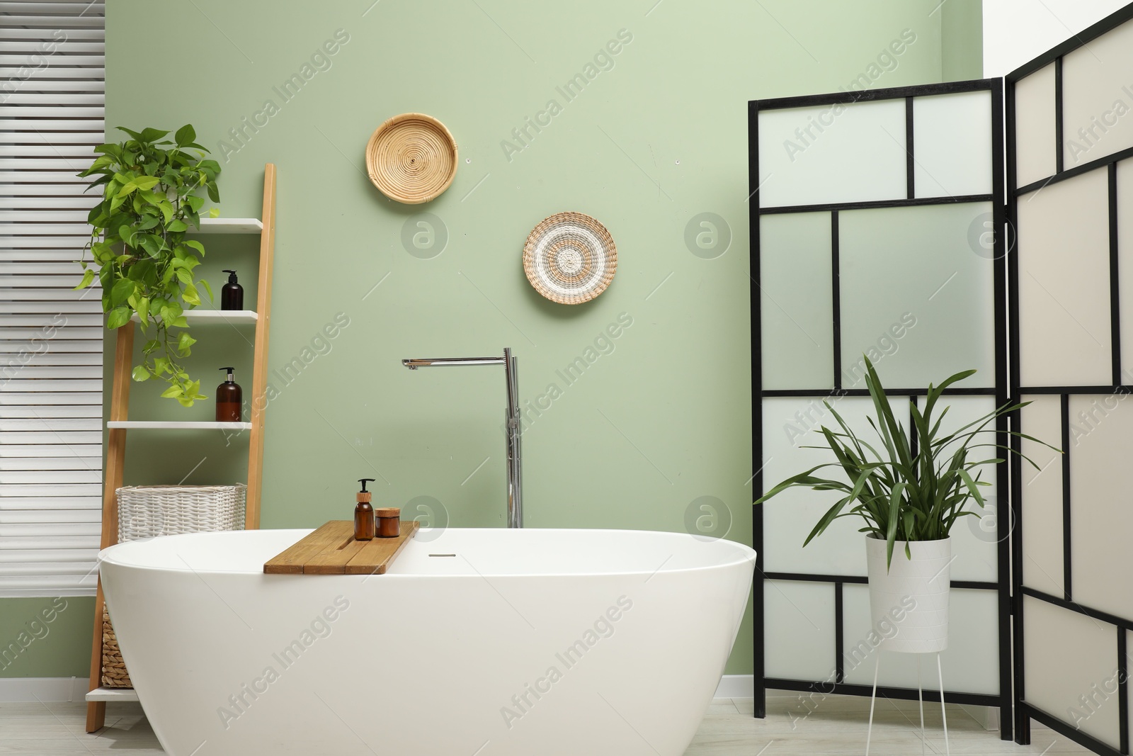 Photo of Stylish bathroom interior with folding screen and tub