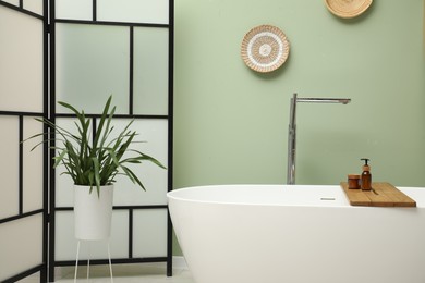 Photo of Stylish bathroom interior with folding screen and tub