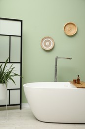 Photo of Stylish bathroom interior with folding screen and tub