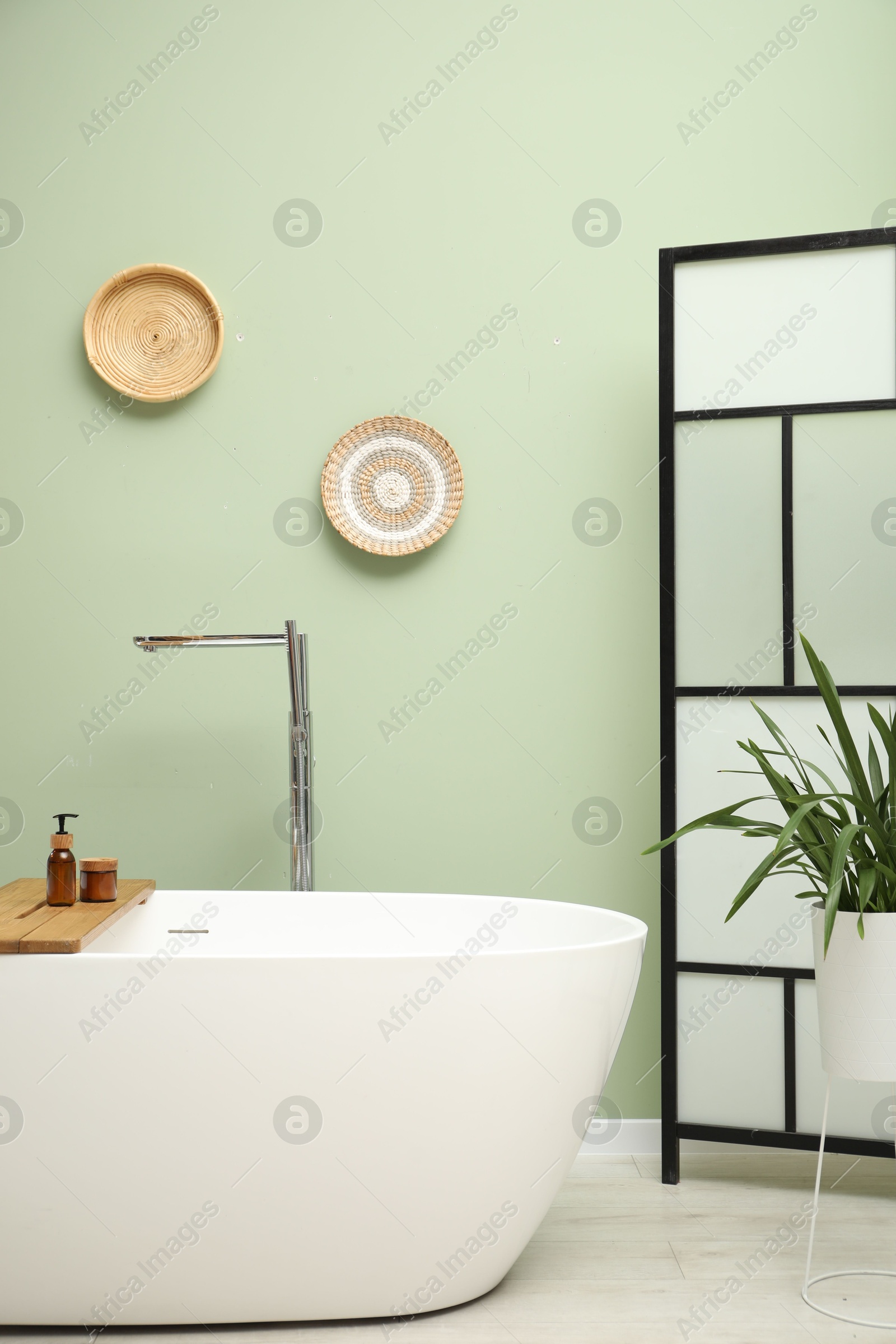 Photo of Stylish bathroom interior with folding screen and tub