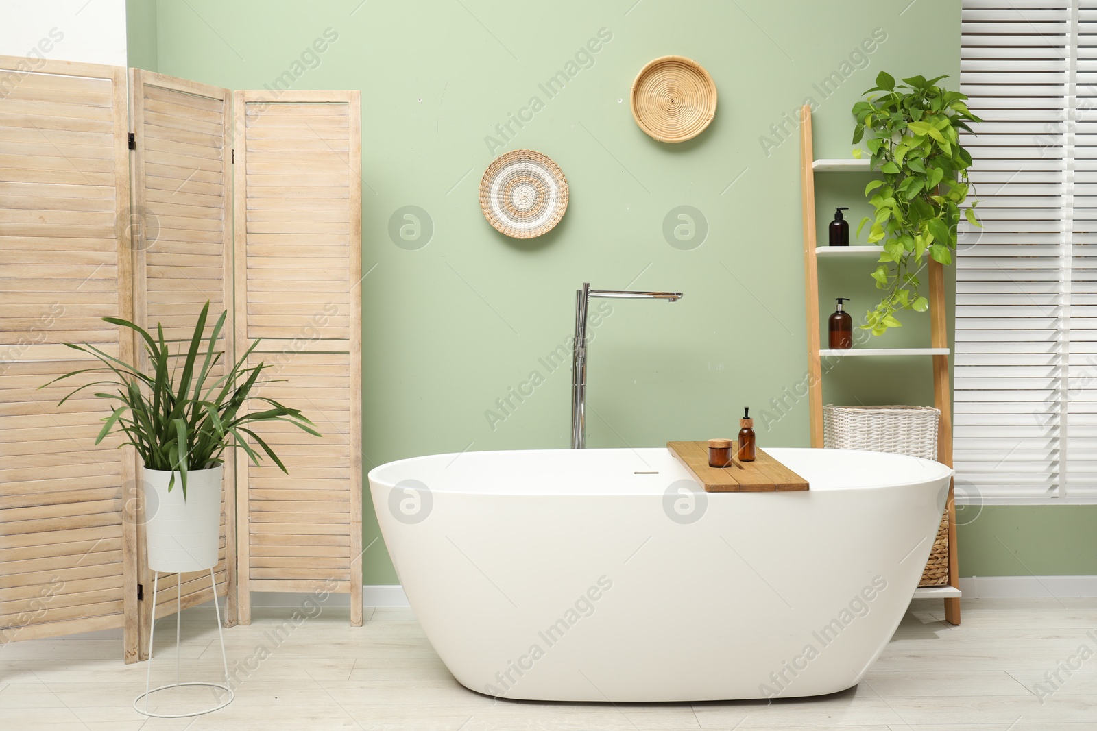 Photo of Stylish bathroom interior with folding screen and tub