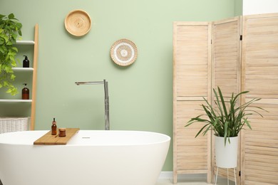 Photo of Stylish bathroom interior with folding screen and tub